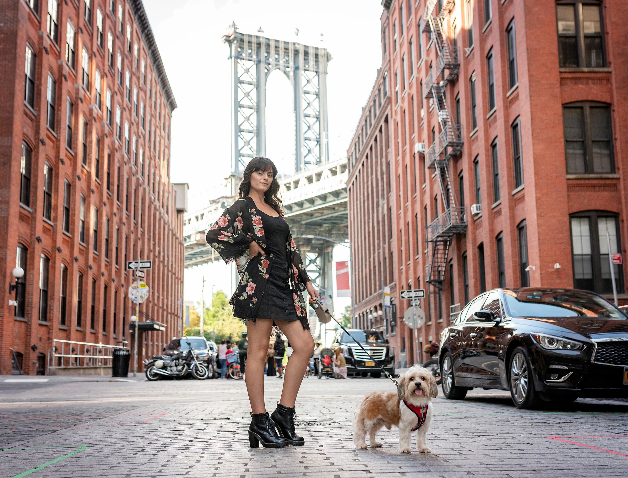 Woman and her dog stand in front of the Manhattan Bridge