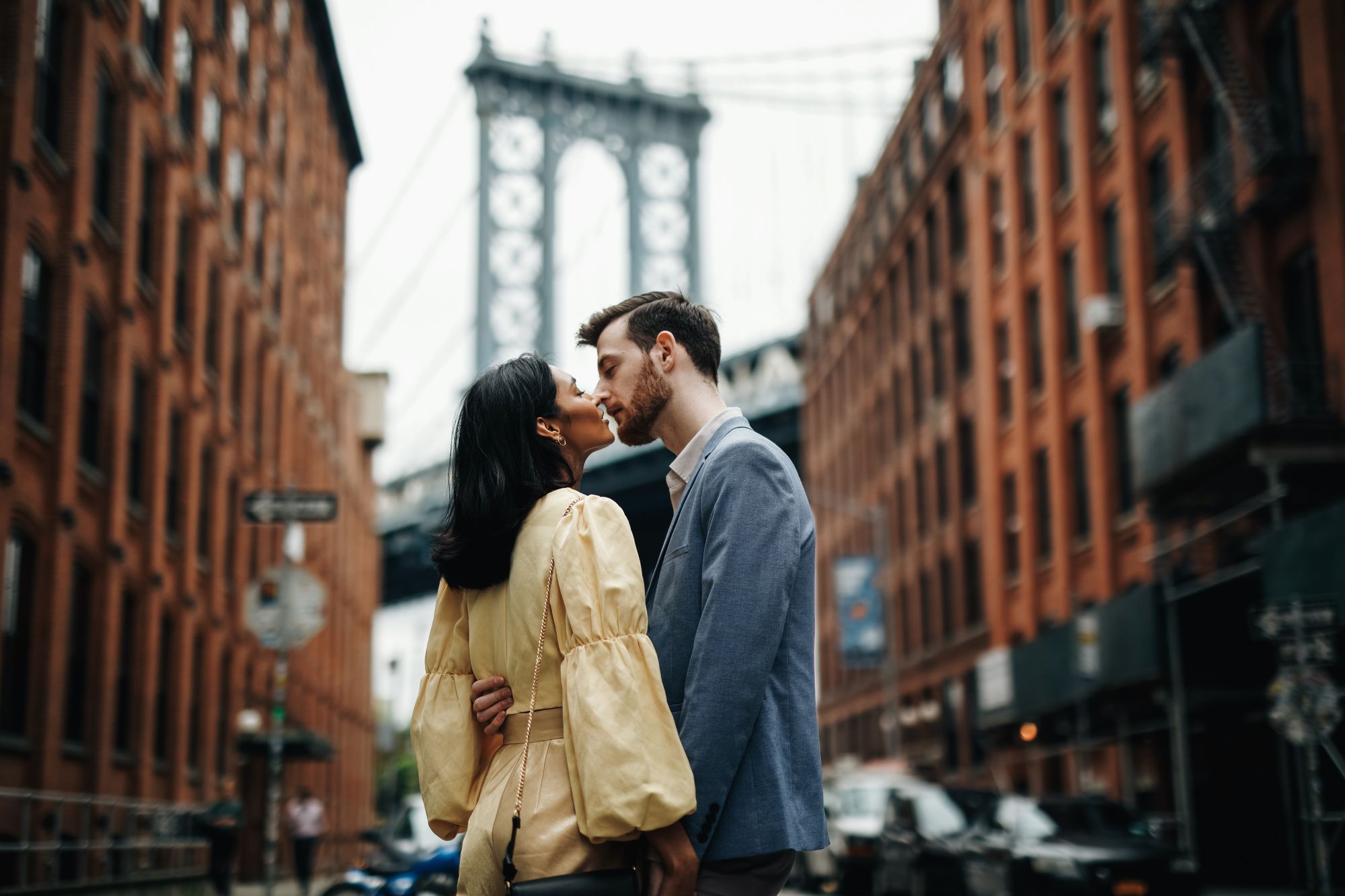 Couple sharing a romantic moment in front of the Brooklyn Bridge