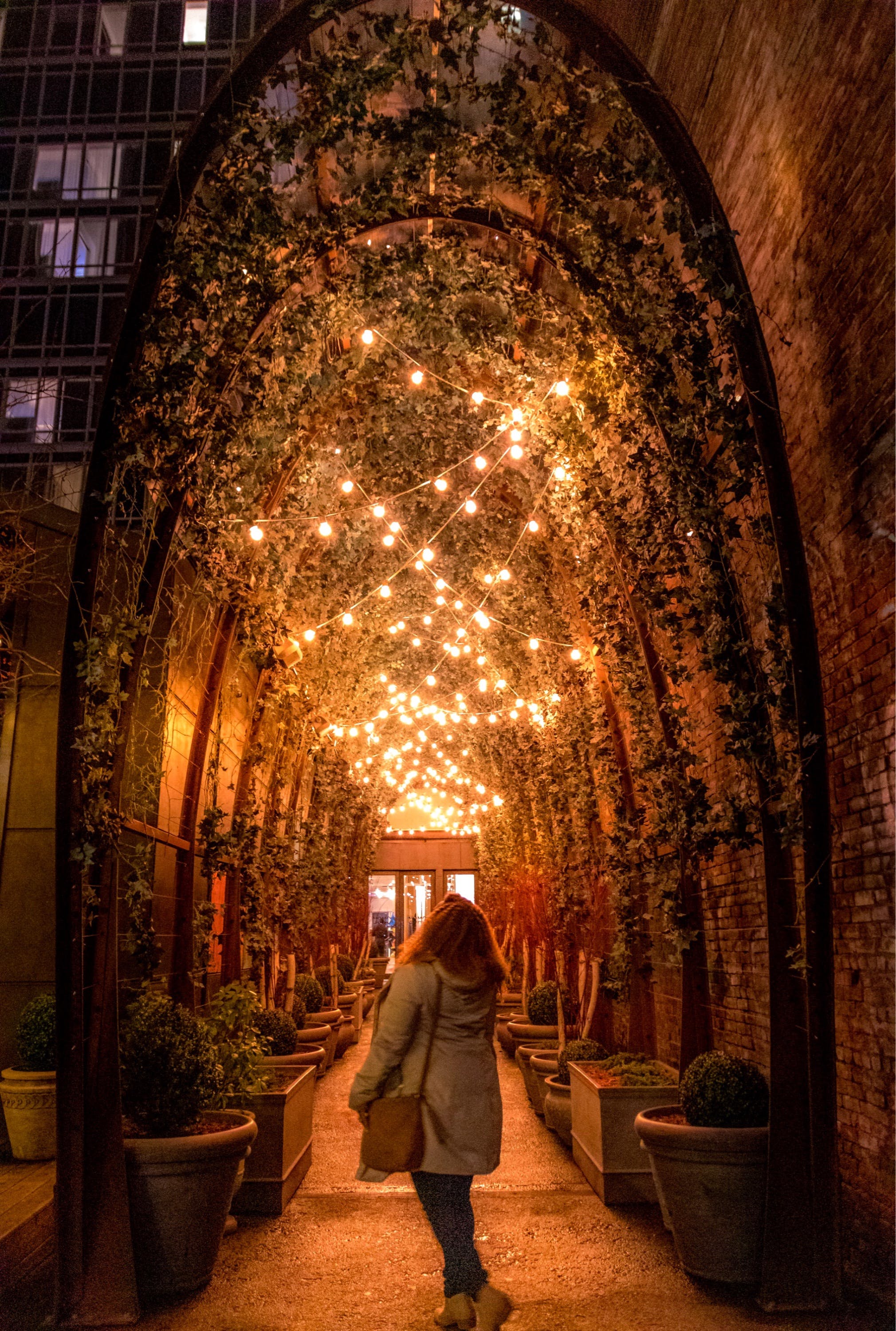 Woman standing underneath fairy lights at hotel entrance