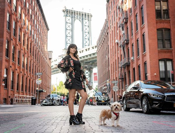 Woman standing in front of Brooklyn Bridge in New York with her dog
